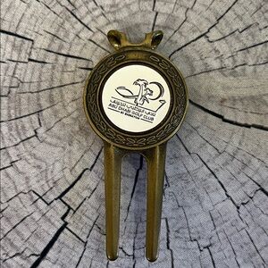 Golf divot repair tool with a ball marker featuring the logo Abu Dhabi Golf Club
